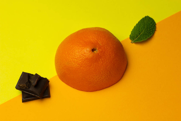 Módní rozložení oranžové, čokoládové a mátové na jasném pozadí. Kombinace ovocné chuti. Tvůrčí koncepce minimalismu. Kopírovat prostor. - Fotografie, Obrázek