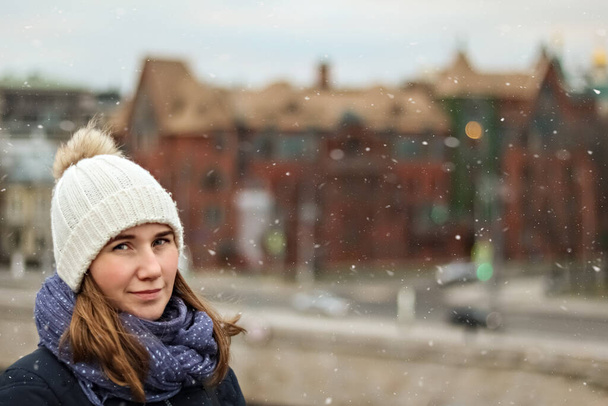 Πορτρέτο ενός νεαρού όμορφο χαρούμενο χαμογελαστό κορίτσι στο παρασκήνιο της πόλης. Χειμερινή μόδα, Χριστούγεννα έννοια διακοπές - Φωτογραφία, εικόνα