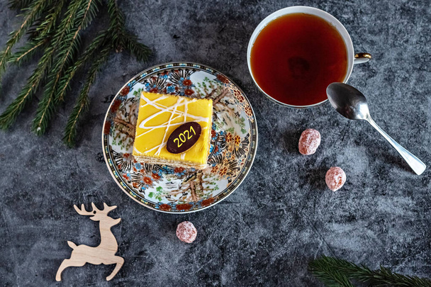 New Year's photo of a cake with tea, dried kumquat on a table with fir branches and toys, postcard. - Photo, Image