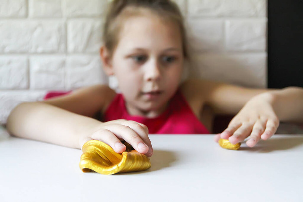 Kleines Mädchen spielt mit dem Goldschleim. Sinnesaktivität für Kinder. - Foto, Bild