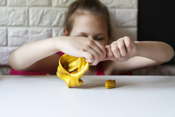 Κοριτσάκι που παίζει με τη χρυσή γλίτσα. Αισθητηριακή δραστηριότητα για παιδιά. - Φωτογραφία, εικόνα