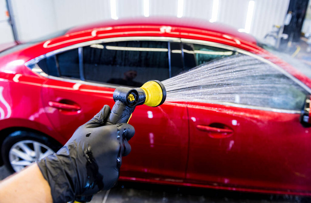Service worker washing car on a car wash. - Фото, изображение