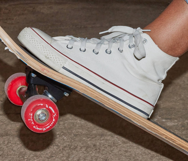 A skateboard with a girl's feet wearing slippers. Girl doing sport on a skateboard. Closed up plane of a sport scene doing skateboard. - Photo, Image