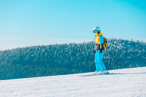 女性は冬の斜面の山を背景にスキーをし - 写真・画像