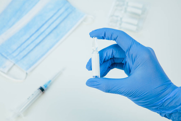 hand in medische handschoenen ampul met vaccin van dichtbij - Foto, afbeelding