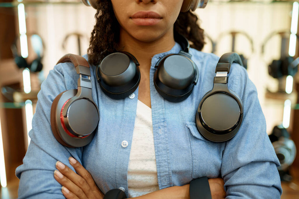 Egy nő fejhallgatóval az audió alkatrész boltban, zene rajongó. Női személy a zeneboltban, bemutatás fülhallgatóval a háttérben, vevő a multimédiás szalonban - Fotó, kép
