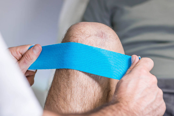 fisioterapia con cinta de cinesiología azul en la rodilla - Foto, imagen