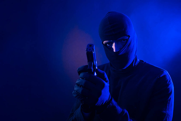 Serie eines kaukasischen Einbrechers, der mit einer Waffe in der Hand in ein Haus eingebrochen ist. Inklusive Polizeibeleuchtung. - Foto, Bild