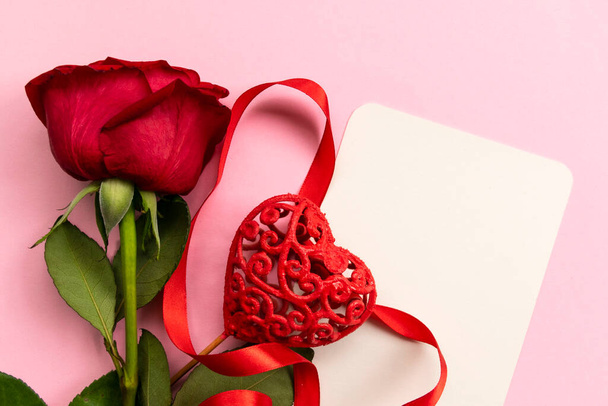 Red rose with decorated heart on pink background. Concept of Valentine's day, mother's day, women's day and birthday. Greetings card. Copy space. Flat lay. - Φωτογραφία, εικόνα