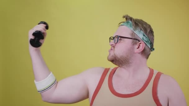 overweight man doing biceps with one hand, eating a cookie with the other. fat funny man - Filmati, video