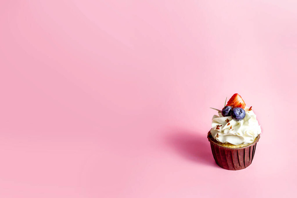 Délicieux cupcake à la crème et aux baies fraîches isolé sur fond rose. Espace de copie. - Photo, image