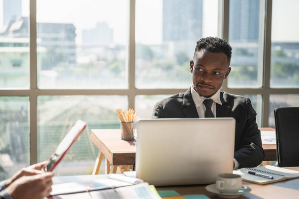 Концепция разнообразия бизнеса и места работы. Молодой африканский бизнесмен с ноутбуком и ноутбуком в офисе - Фото, изображение