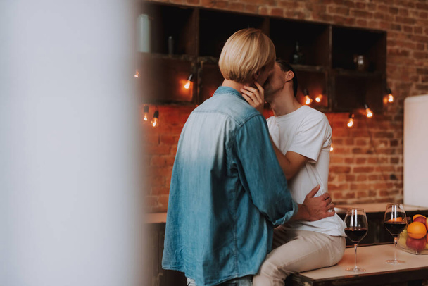 Rakastava homopari kotona. Kaksi komeaa miestä halaamassa ja suutelemassa keittiössä. LGBT-käsite. - Valokuva, kuva