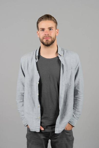 Man bearded strict face wears casual clothes, grey background. Man with beard unshaven guy looks handsome and well groomed casual clothes. Guy bearded attractive with hairstyle. Masculinity concept - Fotoğraf, Görsel