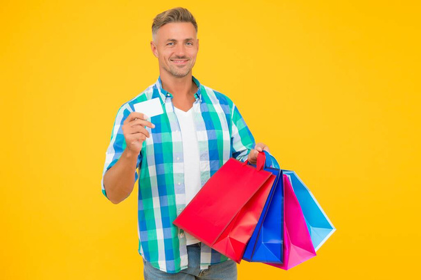 guy with business or credit card. happy man carry shopping bags. black friday. male shopper with packages. prepare for holidays. christmas sales and discounts. birthday present packs. shopaholic - Fotografie, Obrázek