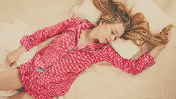 Teenage sleepwear fashion concept. Young woman lying on bed wearing cute pink pajamas. Top view - Photo, Image