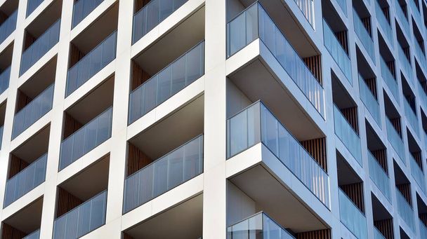 新しいアパートの建物のファサード。ガラスバルコニーと青い空の背景を持つ現代建築の建物のきれいな外観. - 写真・画像