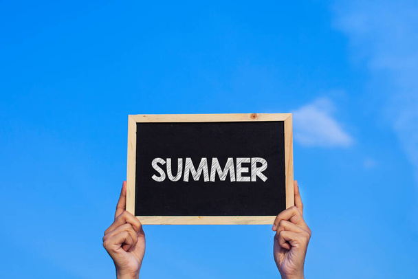 SUMMER / Man met klein schoolbord op blauwe lucht achtergrond - Foto, afbeelding