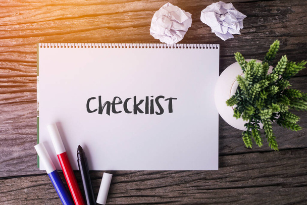 Checklist word with Notepad and green plant on wooden background - Foto, imagen