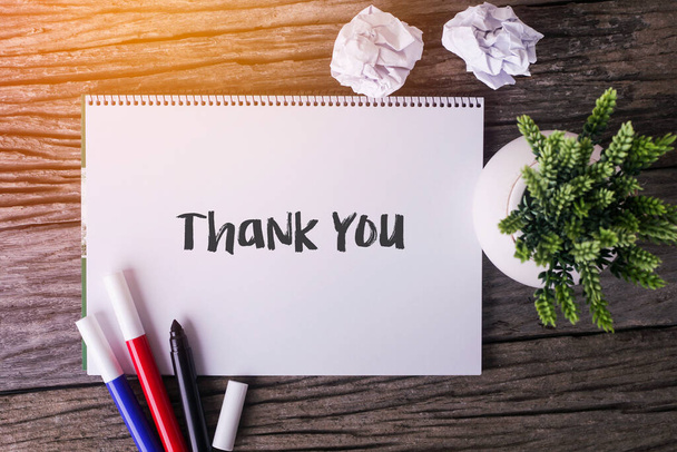 Слово "Спасибо" с блокнотом и зеленым растением на деревянном фоне - Фото, изображение