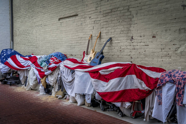 Obdachlose karren Habseligkeiten, die mit einer riesigen amerikanischen Flagge mit blau-weißen und roten Gitarren darauf in Washington DC bedeckt sind - Foto, Bild