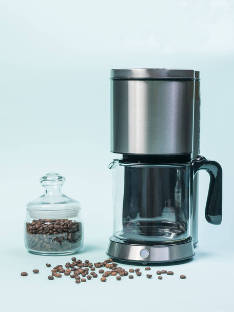 Coffee maker and glass jar with coffee beans on a blue background. The concept of a classic Breakfast. - Photo, Image