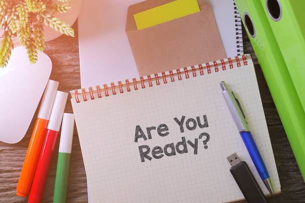 Caderno escrevendo "Você está pronto?" na mesa com espaço de trabalho no escritório com planta, drive USB e óculos - Foto, Imagem