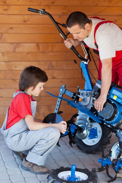 Хлопчик допомагає батькові змонтувати машину для культивації
 - Фото, зображення