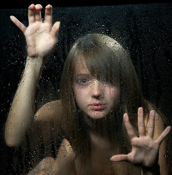 The girl behind glass with rain drops. Focus on drops. - Foto, afbeelding