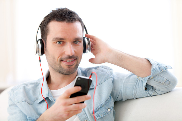 Young relaxed man listening music in a sofa - Photo, Image