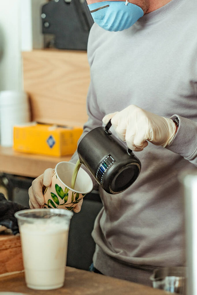 Barista at coffee shop restaurant wearing gloves and mask making drink to-go. New normal, small local business support concept - Fotografie, Obrázek