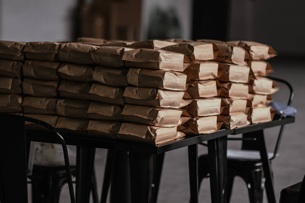 Stos toreb z kawą na czarnym stole na poddaszu. Koncepcja pakowania, przechowywania, dystrybucji - Zdjęcie, obraz