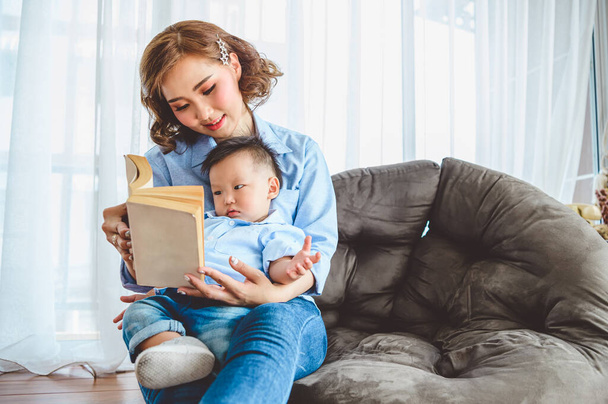Asian mother reading with her son in the living room at home. People lifestyle and leisure activity. Kids and baby concept - Foto, imagen