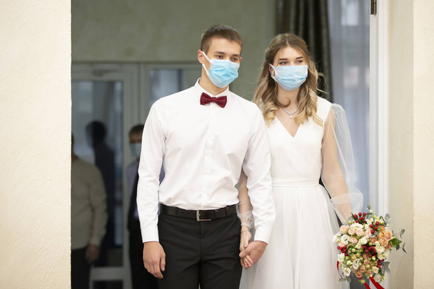 Bride and groom wearing medical masks. Getting married during the coronavirus pandemic. - Photo, Image