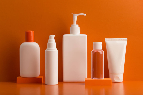 Set of cosmetic products for skin and body care against orange background. Concept of summer or regular skincare - Φωτογραφία, εικόνα