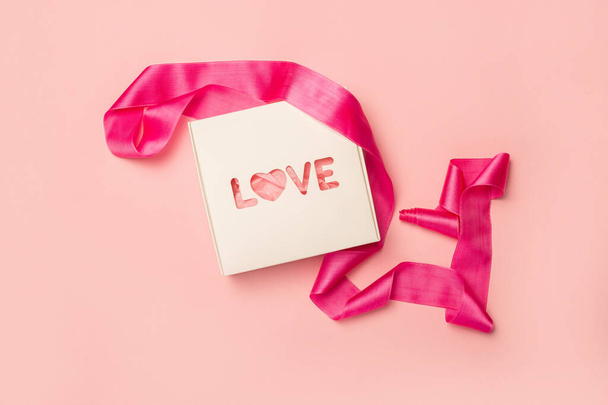 Caixa de presente e fita rosa em um fundo rosa pastel. Composição Dia dos Namorados. Deitado plano, vista superior. Banner. - Foto, Imagem