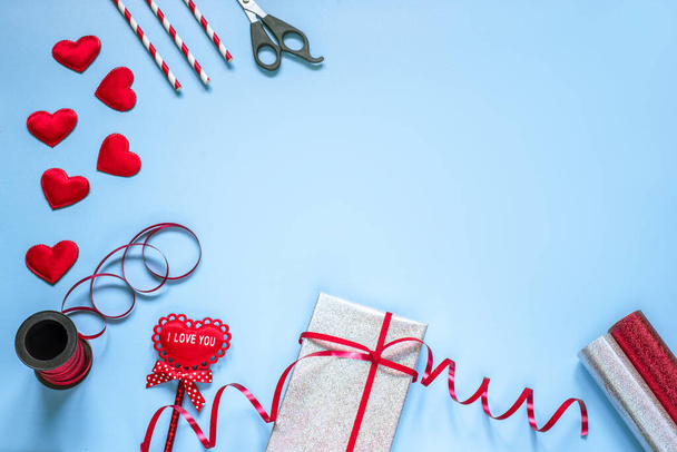 Valentinstag kreatives Layout mit Geschenkpapier auf blauem Hintergrund - Foto, Bild