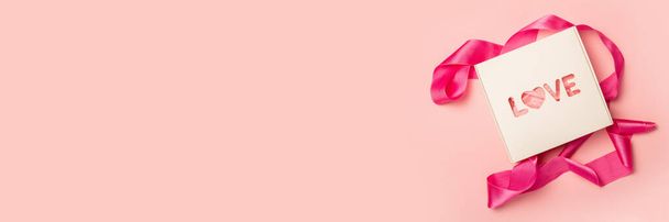 Coffret cadeau et ruban rose sur fond rose pastel. Composition Saint Valentin. Couché à plat, vue de dessus. Bannière. - Photo, image
