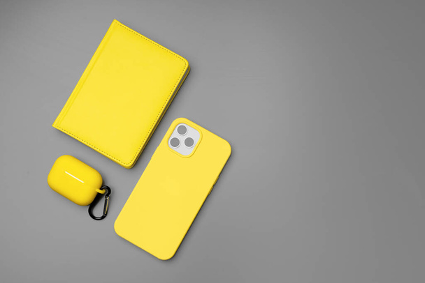 Yellow notepad, smartphone and earphones on gray background - Fotoğraf, Görsel