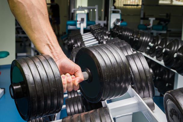 Man doing exercises with dumbbell in the gym. - Photo, Image