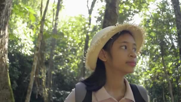 Asian pretty girl wearing straw hat with backpack is hiking in the jungle during summer camping. Travel experience concept. - Video