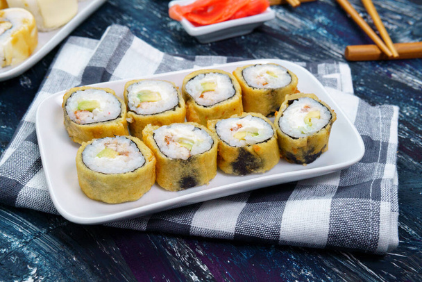 baked sushi rolls with wasabi and ginger on a black background. Japanese oriental cuisine. - Photo, Image