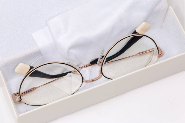 Modern szemüveg a nők fém sárga felni fekszik fehér kemény szemüvegtok szemüveg törlőkendő, közelkép szelektív fókusz - Fotó, kép