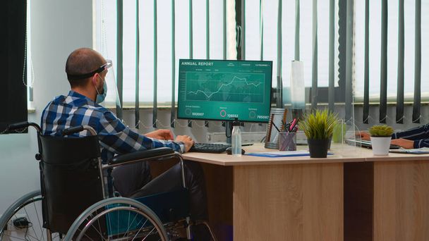 Empresario en silla de ruedas con máscara de protección en el lugar de trabajo - Foto, Imagen