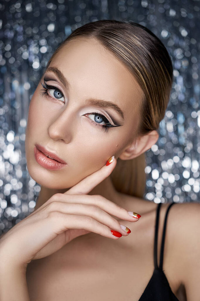 Beautiful evening eye makeup of a blonde woman on a shiny background. Close-up portrait of a woman, perfect eye makeup, skin care - Фото, изображение