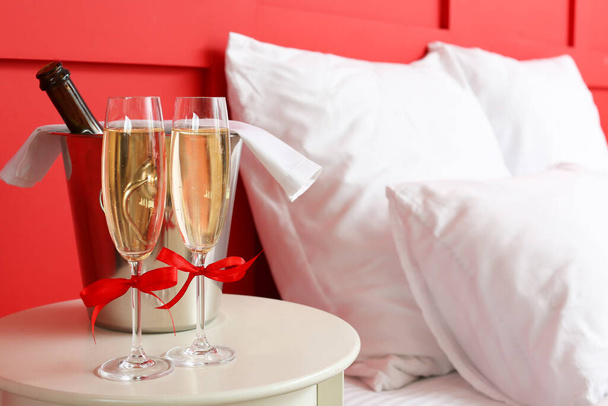 Glas champagne en ijsemmer op tafel in hotelkamer - Foto, afbeelding