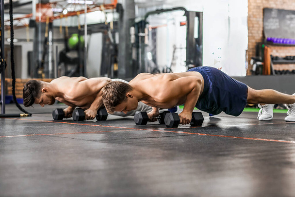Handsome muscular men exercising with dumbbells in gym - Zdjęcie, obraz