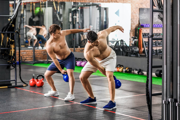 Handsome muscular men exercising with kettlebell in gym - Photo, image