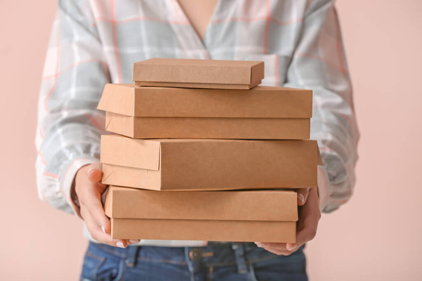 Woman with cardboard boxes on color background - Photo, Image