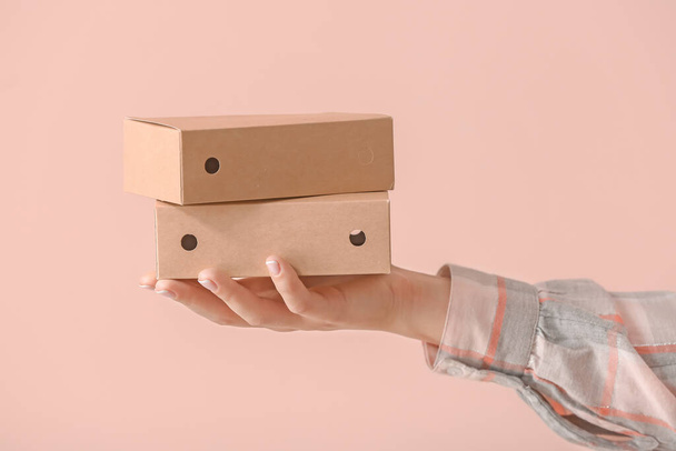 Hand with cardboard boxes on color background - Photo, Image
